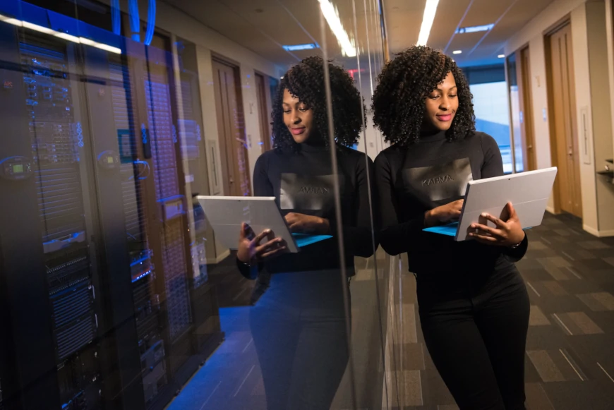 A woman standing outside a server room on her laptop